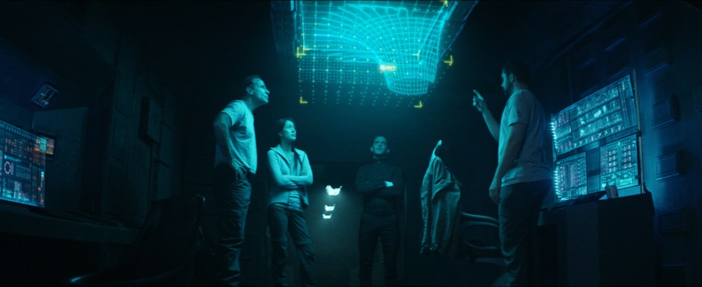 Captain McKay (David M. Edelstien), Moira, Cole and Andrew Jensen (Ben Kliewer) study a holographic display that offers clues as to their predicament.