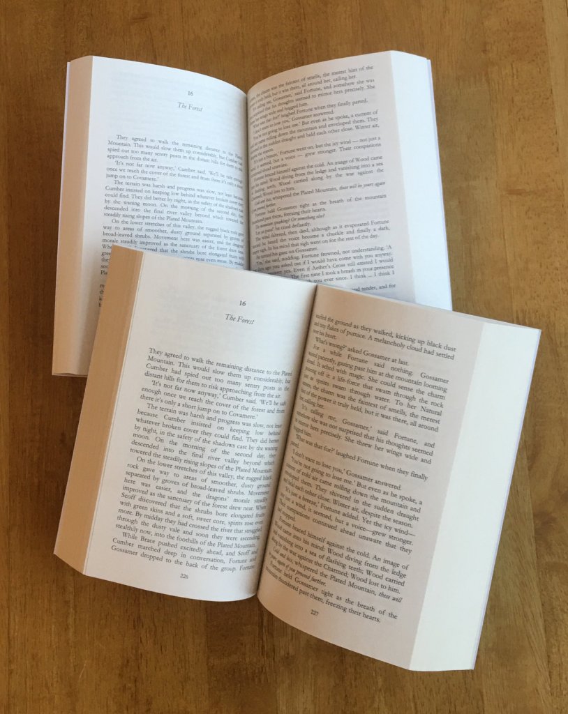 Dragoncharm Special Edition, old and new. The book on top is the 2026 updated version, printed on Amazon’s new groundwood paper.